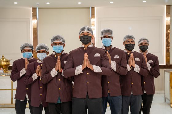 The service team lined up in maroon bandhgala uniforms, greeting guests with folded hands